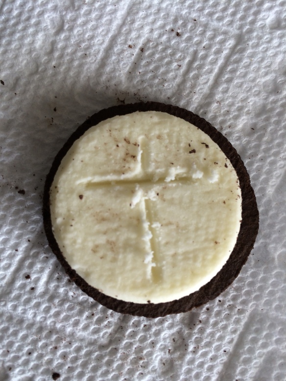 Open Oreo cookie with the shape of a cross etched into the creme filling